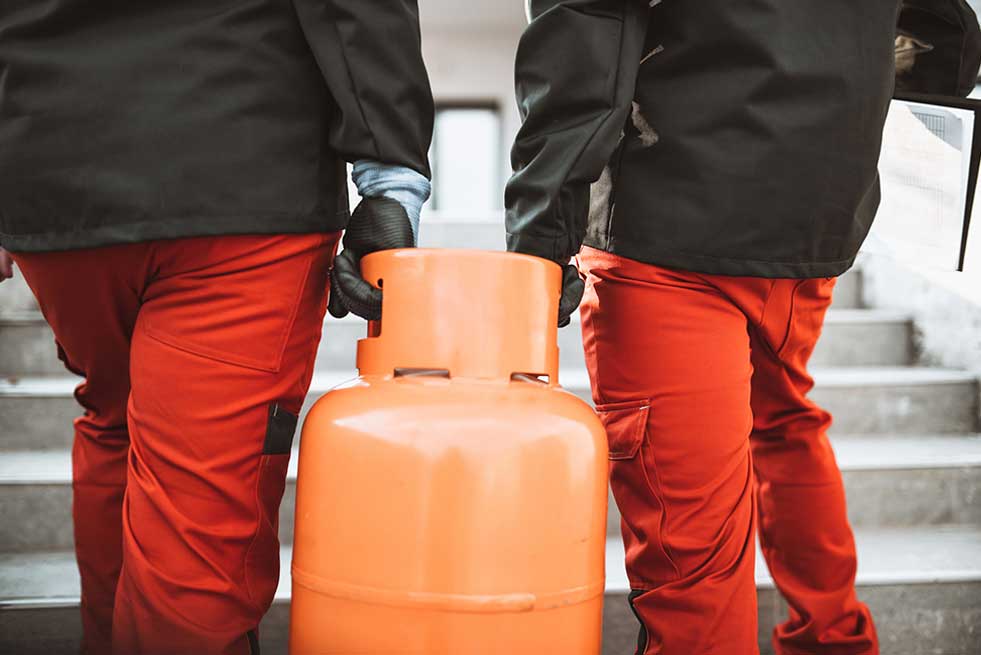 men lifting gas tank